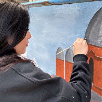 Amanda Päivinen maalaamassa muraalia Lappeenrannan poliisitalon vieressä.