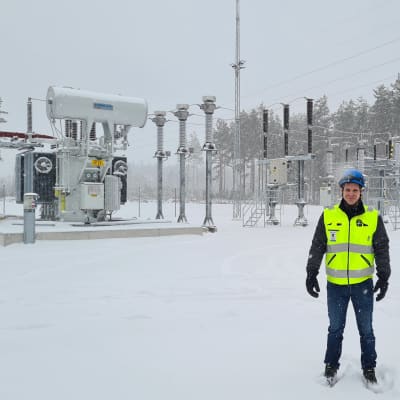 En man i skyddsväst och hjälm står i snön utanför en elstation. Han heter Andreas Talling.