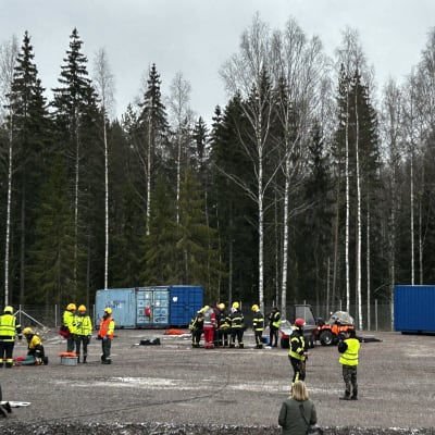 Hiekkakentällä palomiehet auttavat loukkaantuneita suuronnettomuusharjoituksessa.