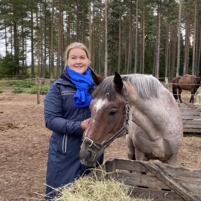 Niina Kirjorinne on yhdessä hevosen kanssa aamuheinien äärellä. Taustaööa näkyy pari muutakin hevosta ulkoaitauksessa.