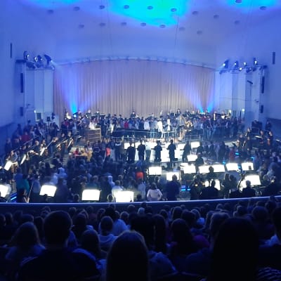Åbo konserthus är upplyst i blå färger då Åbo filharmoniska orkester har en öppen konsert, där publiken får gå runt mellan musikerna.