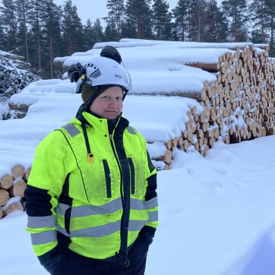 Metsätalousinsinööri Hanna Kangasaho tukkipuukasan edessä talvisessa maisemassa.