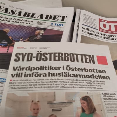 Tidingarna Vasabladet, Syd-Österbotten och Österbottens tidning i högar på ett bord.