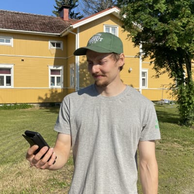Sotkamolainen  Kokkovaaran tilan isäntä Janne Hyvönen katsoo älypuhelinta.