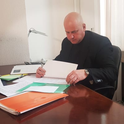 Aleksej Maksimov sitter vid sitt skrivbord och ordnar med papper.