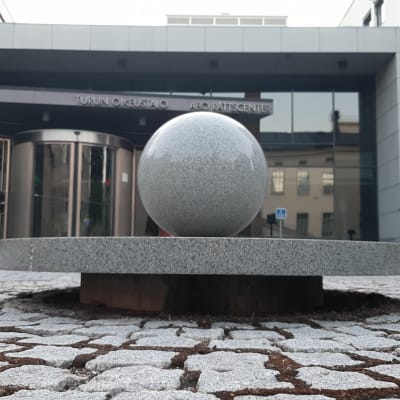 Ett stort grått stenklot pryder innergården framför glasdörrarna till Egentliga Finlands tingsrätt i Åbo.
