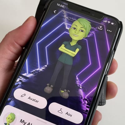Kädessä on älypuhelin, jonka näytöllä näkyy Snapchatin virtuaaliystävä My AI