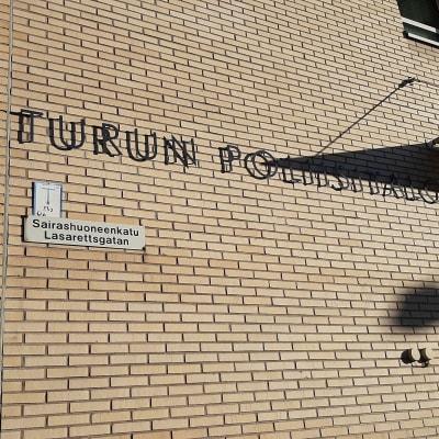En skylt med texten Turun Poliisilaitos på Åbo polisstations gula tegelvägg.