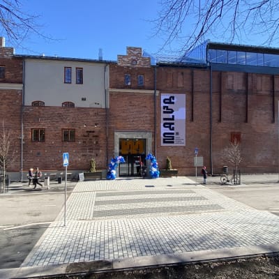 Malvan taidemuseo edestäpäin kuvattuna avajaispäivänä 29.4.2022. Aurinkoinen sää, sininen taivas, ovenpielessä ilmapalloja.