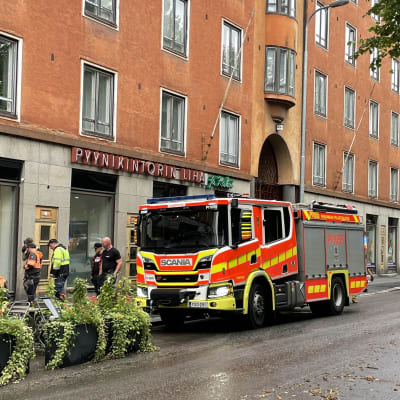 Paloautoja pysäköitynä Tampereen Pyynikintorilla kadunlaitaan. Kävelytiellä seisoo työmiehiä, ja maa on märkää.