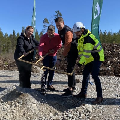 Neljä ihmistä pitelee erikoislapiota tuulivoimalatyömaalla.