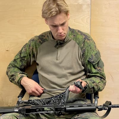Varusmies puhdistaa asettaan.