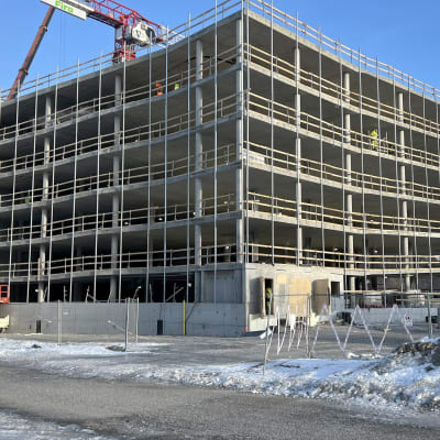Lahden Ranta-Kartanoon rakenteilla oleva betoninen pysäköintilaitos helmikuussa 2023, aurinkoinen päivä, rakennuksen takaa pilkottaa nosturin varsi.