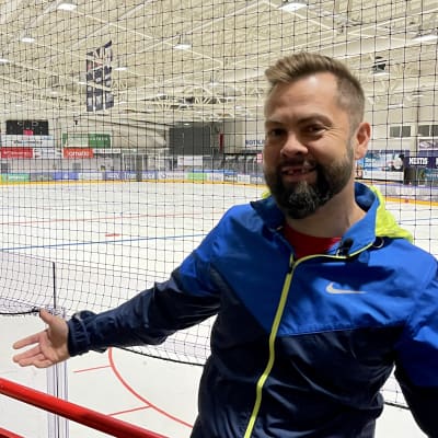 Mies seisoo jääkiekkokaukalon laidalla.