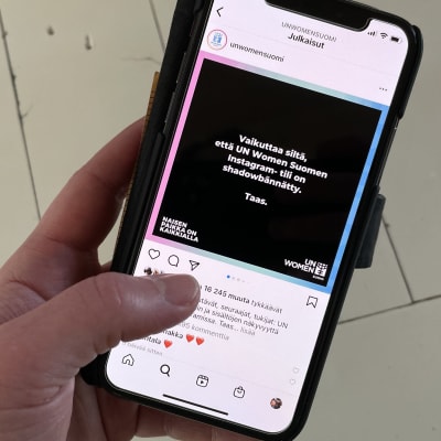 Käsi pitelee älypuhelinta, jossa näkyy UN Women Suomen Instagram-päivitys.