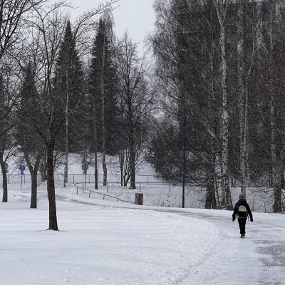 Person går genom en snöig park.