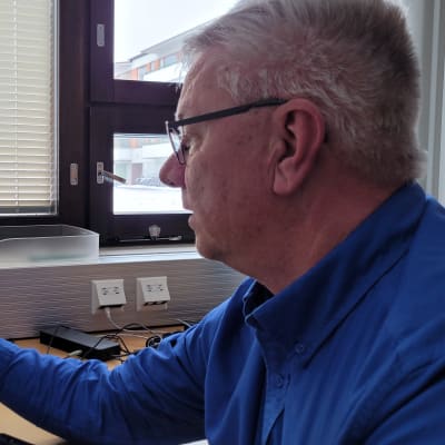Mies osoittaa sormella tietokoneen näytöllä näkyviä sähkönkulutuskäyriä.