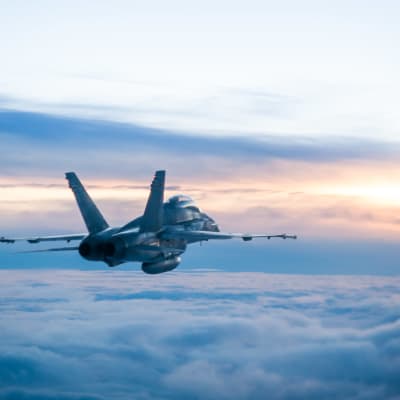 Ett Hornet-jaktplan från finska flottan flyger ovan molnen.