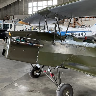 Vanha Suomen ilmavoimien vihreä lentokone seisoo konehallissa.