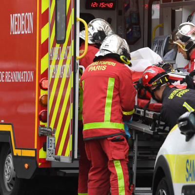 Räddningspersonal lyfter en en sjukhusbår i ambulansen i Paris.
