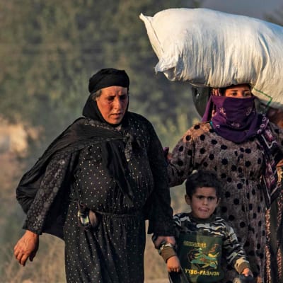 Kvinnor och barn flyr i norra Syrien. På bilden syns fyra barn och fyra kvinnor. En av kvinnorna bär ett större bylte på huvudet. 