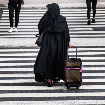 Kvinna i burka går över gata.