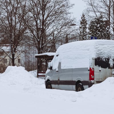 Harmaa korkea pakettiauto pysäköitynä lumivallin keskelle Jyväskylässä.