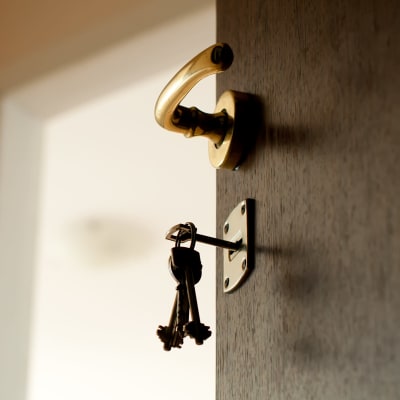 En nyckelknippe hänger i låset på en öppen dörr.