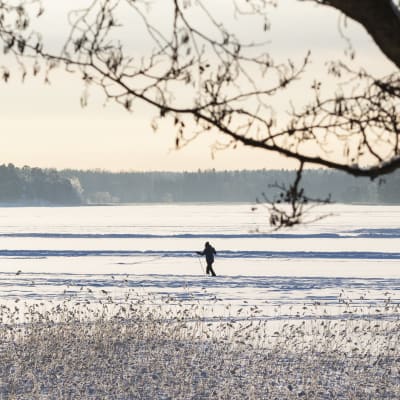 Talvinen maisema meren jäältä jossa kävelee ihmisiä.