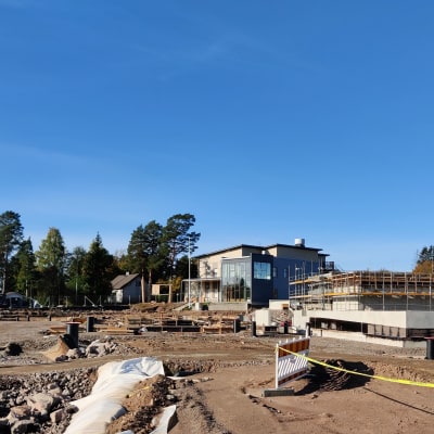 Avaralla työmaalla on hiekkainen kenttä, jolla on rakennuspressua, esteaitaa ja putkia.
