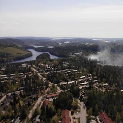 Ilmasta otetussa maisemakuvassa näkyy metsää ja vasemmalla järvi, keskellä kuvaa näkyy savu laajaalla alueella.