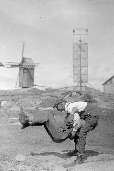 Två män leker leken "prova styrka", där den ena ska lyfta upp den andra. Bilden är tagen 1933 på Björkö, Åland.
