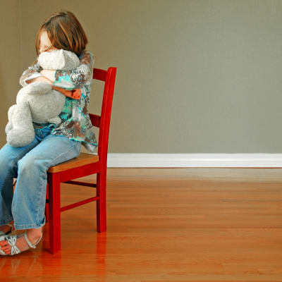 Ett ensamt barn kramar ett mjukisdjur. 