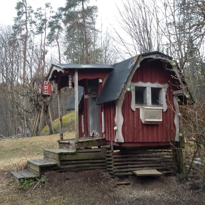 Ett rött hus med vita knutar  i storlek av lekstuga gjord för fåglar. Här finns också talgbollar och fröautomat för fåglar.