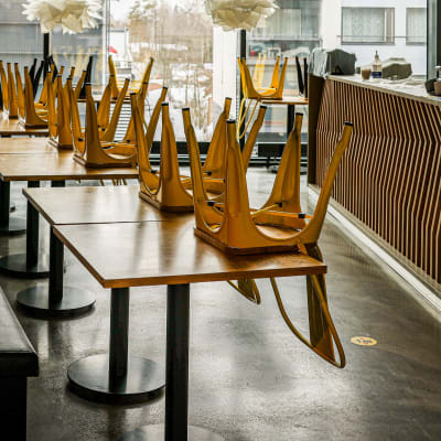 Stolar har placerats upp och ner på borden i en restauranglokal. 