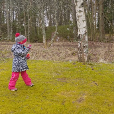 Elvi Sihvonen puhaltelee saippuakuplia kotipihalla.