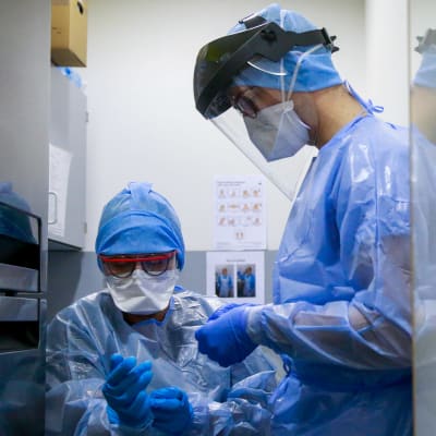 Två hälsovårdare klär sig i skyddsutrustning vid sjukhuset i den belgiska staden Marche-En-Famenne