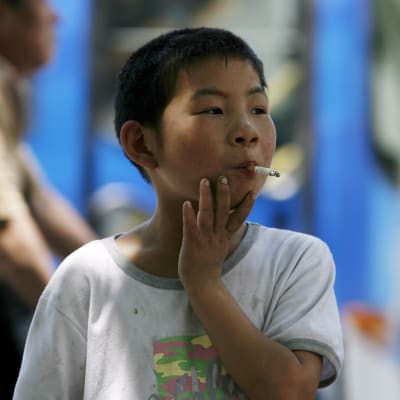 En sjuårig kinesisk pojke röker en cigarrett i centrala Peking.
