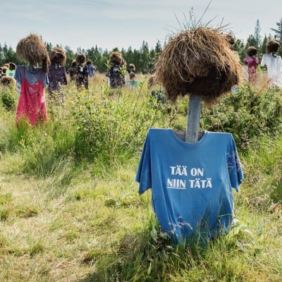 Hiljainen kansa -teoksen heinäseiväshahmo, jolla t-paita, jossa teksti "Tää on niin tätä".