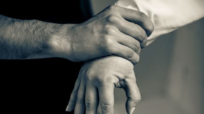 en manlig hand håller hårt on en kvinnas hand