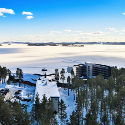 Kylpylähotelli talvisessa maisemassa järven rannalla.