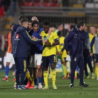En hög med svenska och italienska ledare och spelare diskuterar efter en match.