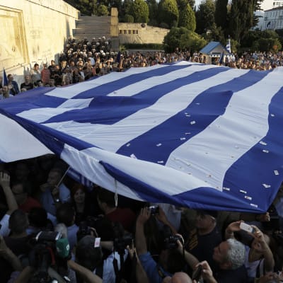 Demonstranter som vill att Grekland stannar kvar i EU håller upp den grekiska flaggan utanför parlamentet i Aten.