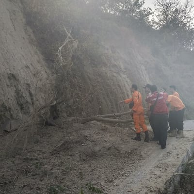 Räddningsarbetare röjer undan bråte på bergsvägar efter jordskalv och jordskred för att på folk som sitter fast på den aktiva vulkanen 