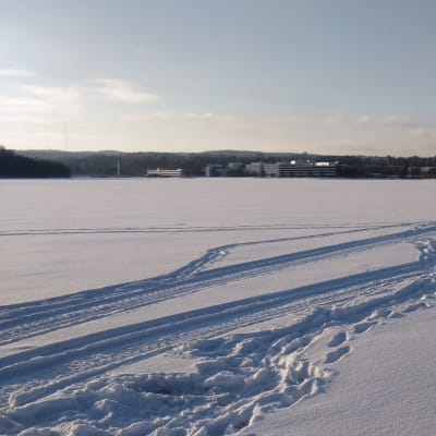Jyväsjärven jäällä moottikelkan jälkiä lumessa. 