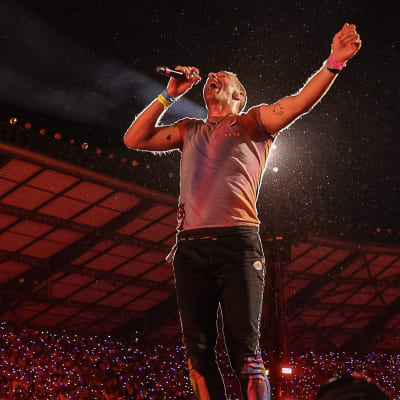 Sångaren Chris Martin i Coldplay hoppar på scenen och sjunger upp i luften.