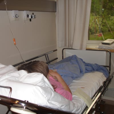 En ungdom som ligger i en sjukhussäng på barnavdelningen.