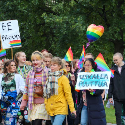 Pride-parad. Flera ungdomar med regnbågsflaggor.