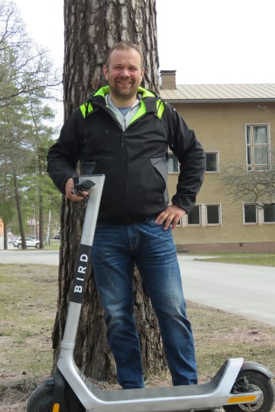 En man står bredvid en elsparkcykel, Fredrik Bäcklund.
