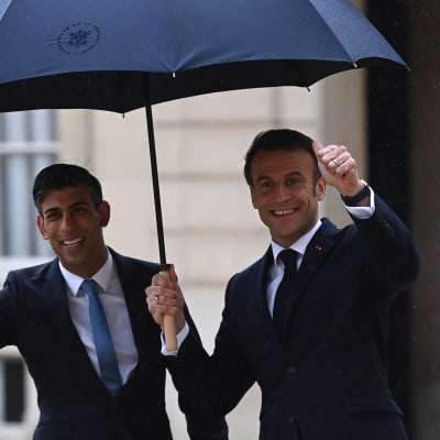 Frankrikes president Emmanuel Macron och Storbritanniens premiärminister Rishi Sunak under ett paraply.